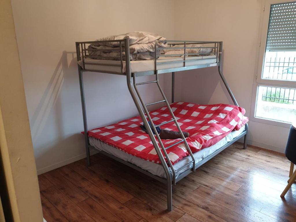 a bunk bed in a room with a red and white blanket at Studio à 1 kilomètre de Disneyland Paris in Montévrain