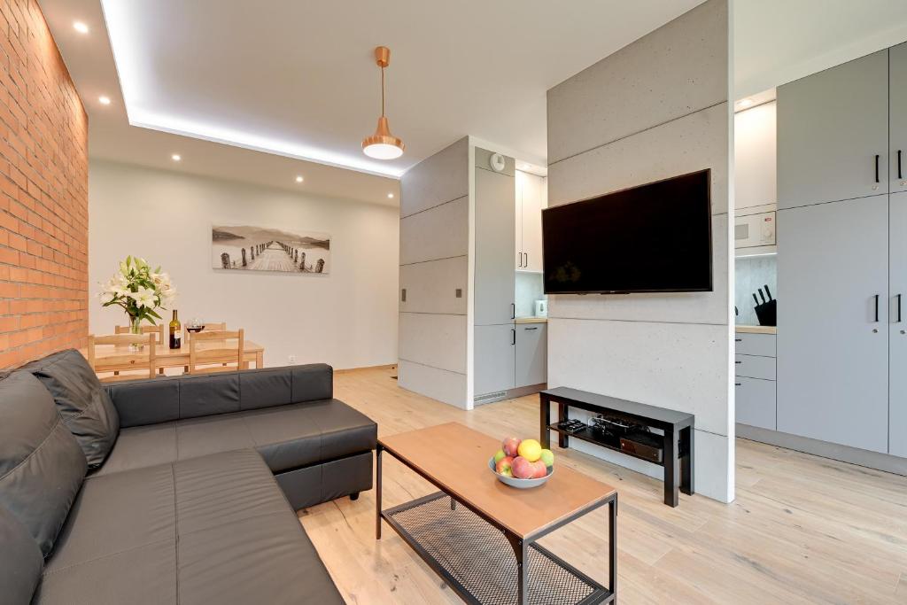 a living room with a couch and a television and a table at Central Apartment - free private parking in Gdańsk