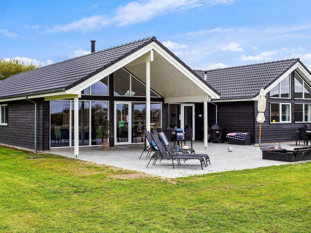 a house with a patio with chairs and a grill at Holiday Home in Zealand with Private Pool in Marielyst