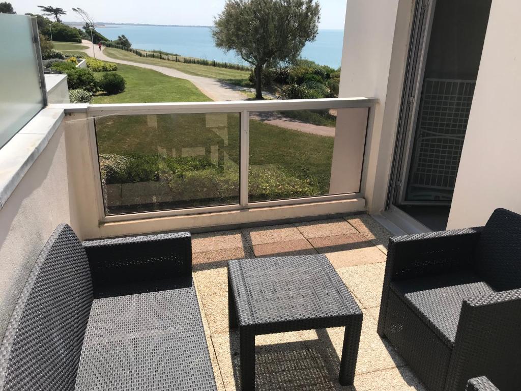 einen Balkon mit 2 Stühlen, einem Tisch und einem Fenster in der Unterkunft Appartement vue imprenable in La Rochelle