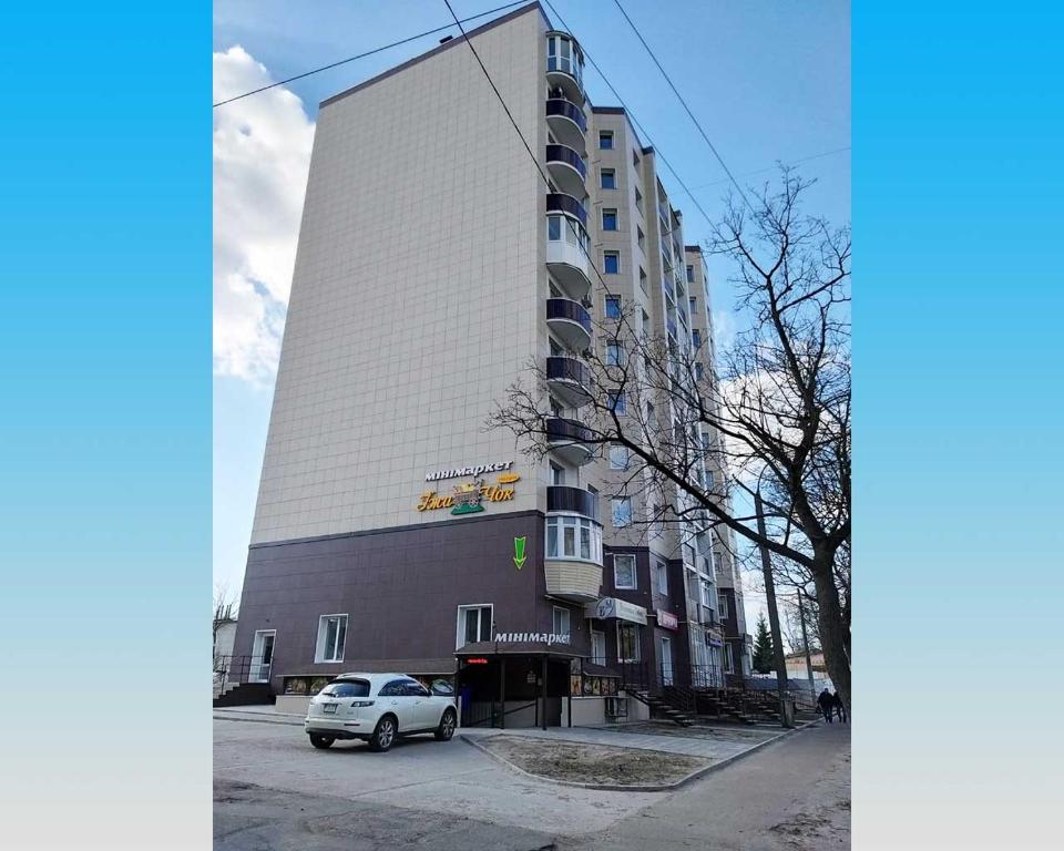 una macchina bianca parcheggiata di fronte a un edificio di Molex Apartments 3 a Černihiv