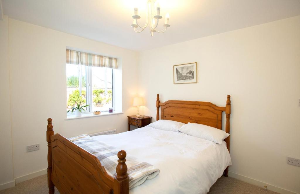 um quarto com uma cama de madeira e um lustre em PERFECT BUSINESS ACCOMMODATION at SIDINGS FARM - Luxury Cottage Accommodation - Self Catering - Secure Parking - Fully equipped Kitchen - Towels & Linen included em Pidley