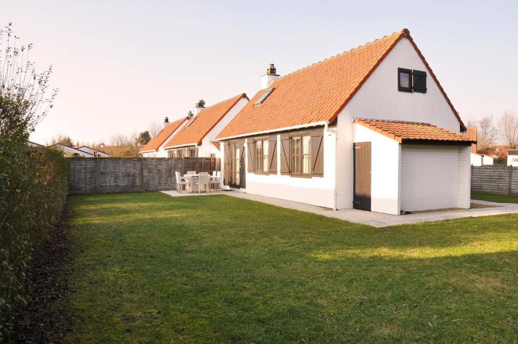 ein weißes Haus mit einem orangenen Dach und einem Hof in der Unterkunft Zeepark Zeewind in Bredene