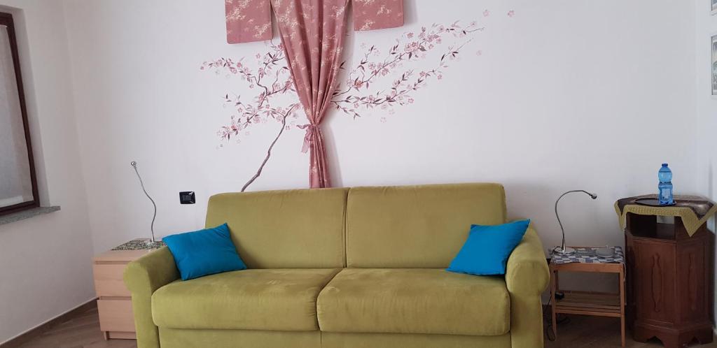 a living room with a green couch and blue pillows at Monolocale Candiolo in Candiolo