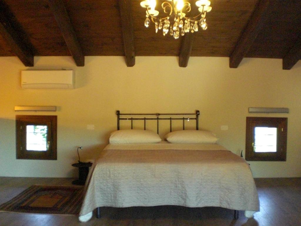 sypialnia z dużym łóżkiem i żyrandolem w obiekcie Venezia delle Nevi w mieście Budòio