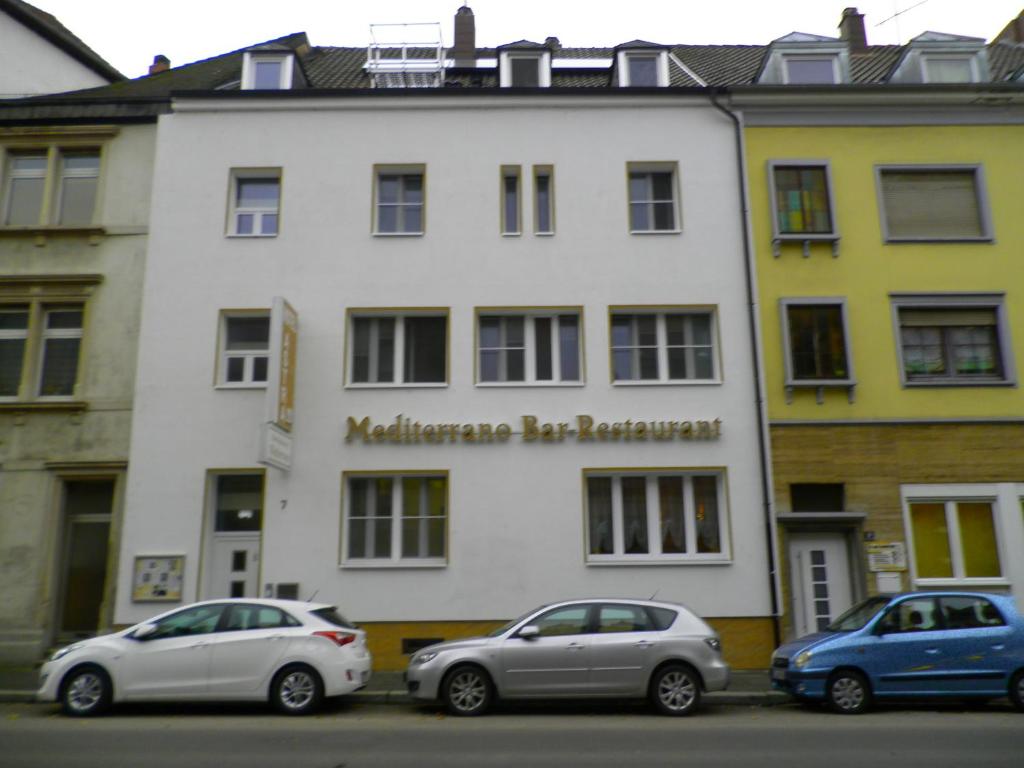 dos autos estacionados frente a un edificio blanco en Astra Hotel, en Kaiserslautern