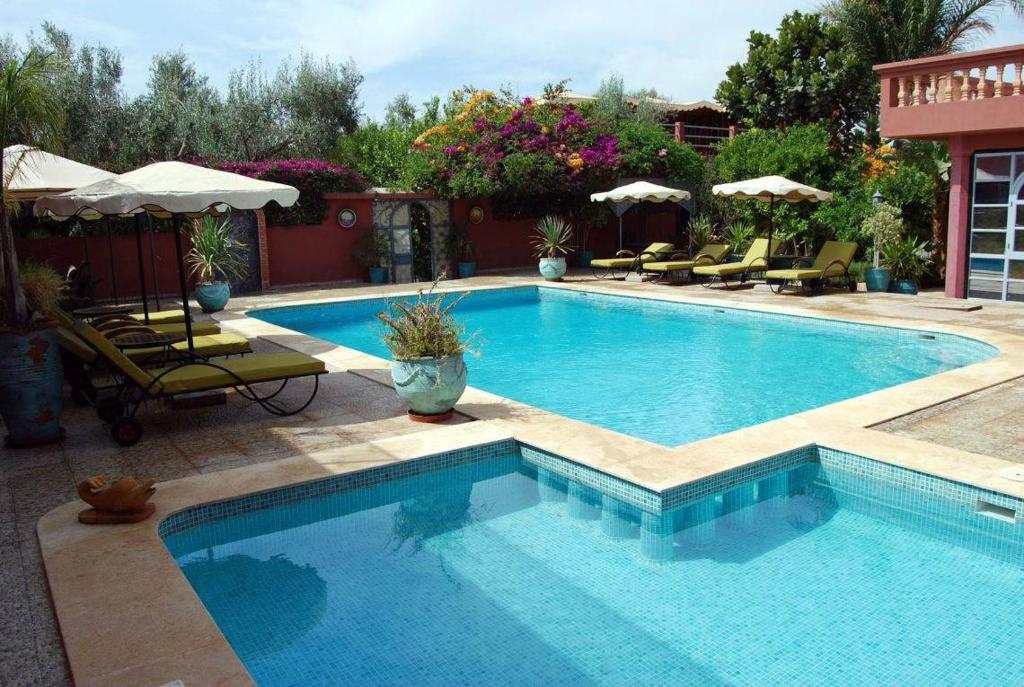 a swimming pool with chairs and umbrellas in a yard at Riad les jardins Mabrouk in Taroudant