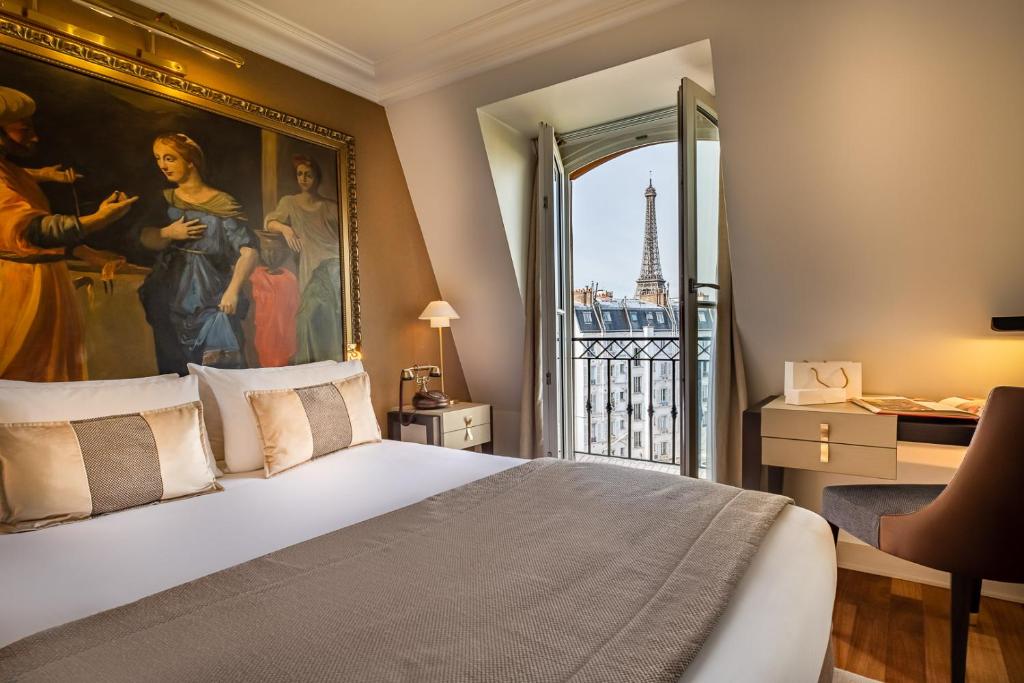 a hotel room with a large bed and a painting on the wall at Hôtel Le Walt in Paris