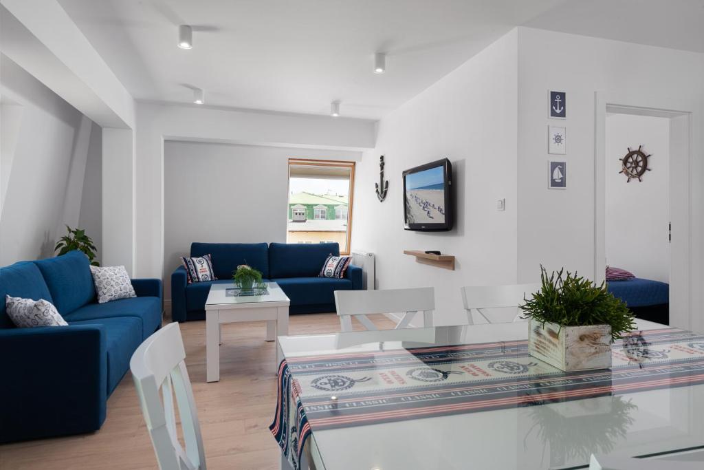ein Wohnzimmer mit einem blauen Sofa und einem Tisch in der Unterkunft Apartament Biała Kotwica in Jastrzębia Góra