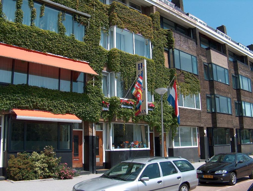 twee auto's geparkeerd voor een gebouw met klimop bij Hotel Baan in Rotterdam