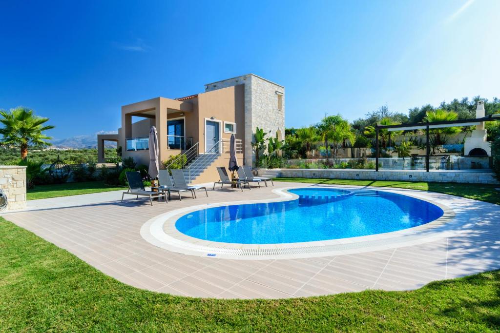 a villa with a swimming pool in front of a house at Villa Thalia in Stalos