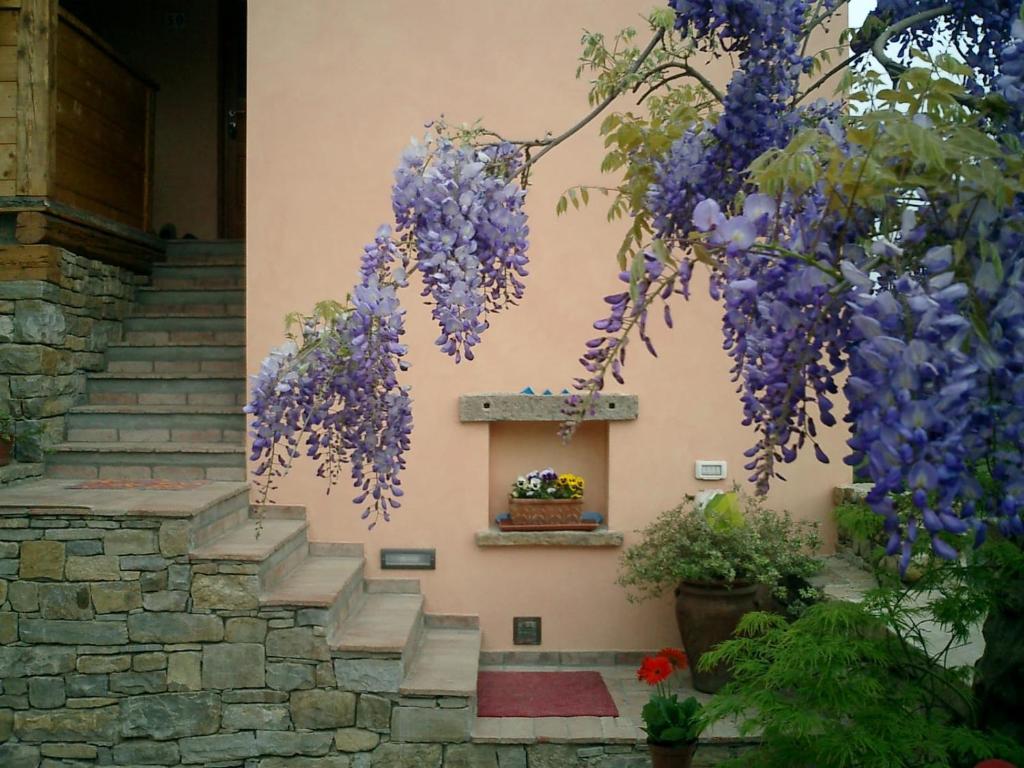 una corona de flores púrpuras colgando de un edificio en Il Glicine, en San Dorligo della Valle