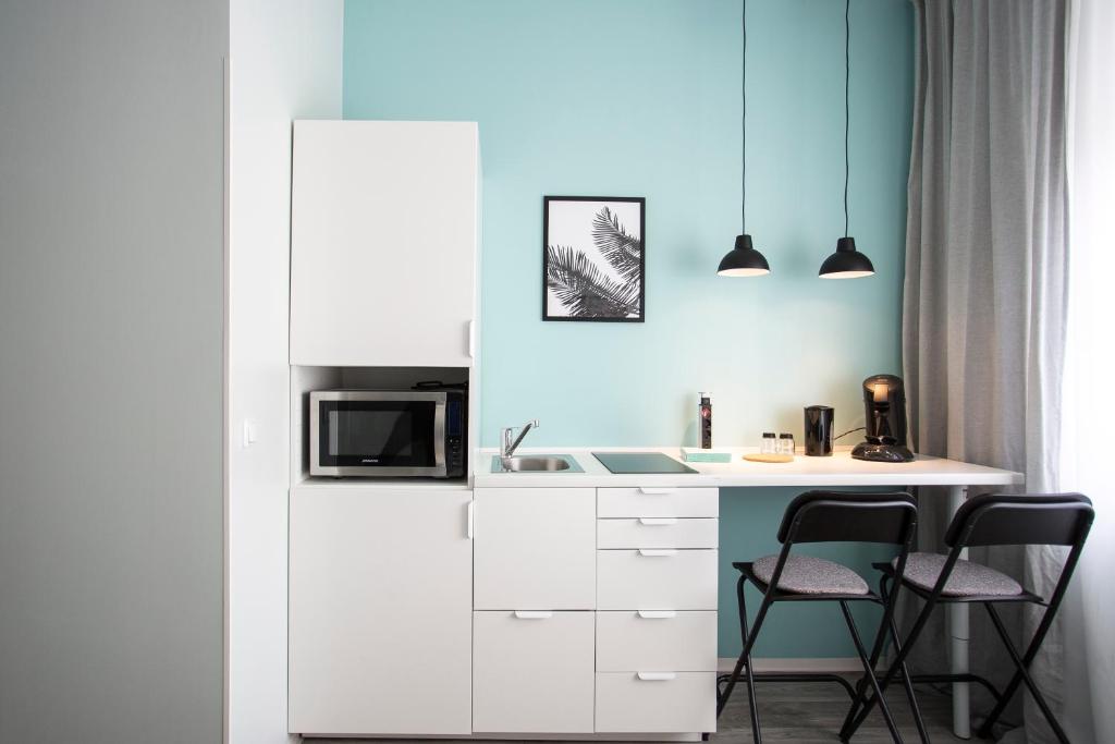 een keuken met een wit aanrecht en 2 stoelen bij Studio Apartments nahe Messe in Neurenberg