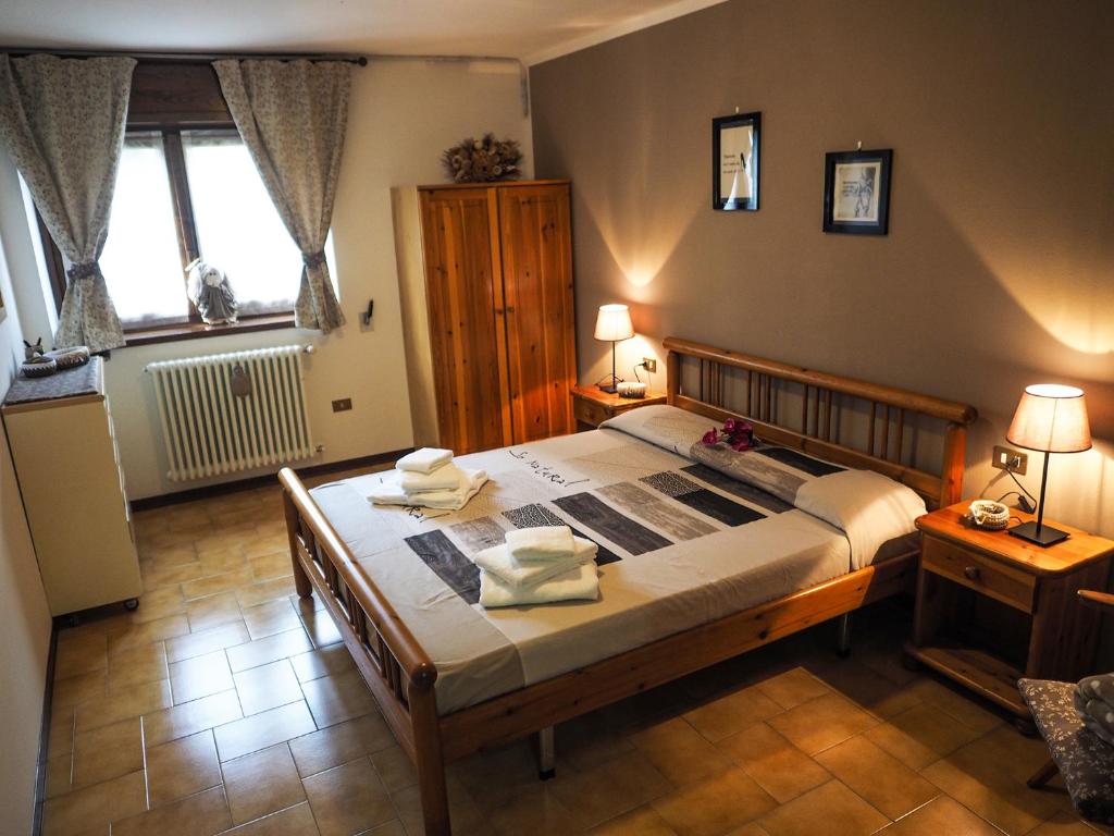 ein Schlafzimmer mit einem großen Bett mit zwei Tischen und zwei Fenstern in der Unterkunft Paradiso della Bici in Morbegno