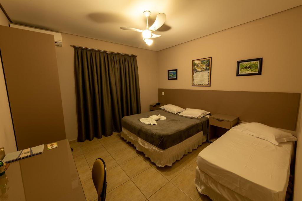 een hotelkamer met 2 bedden en een plafondventilator bij Pousada Villa da Mata in São Miguel Arcanjo