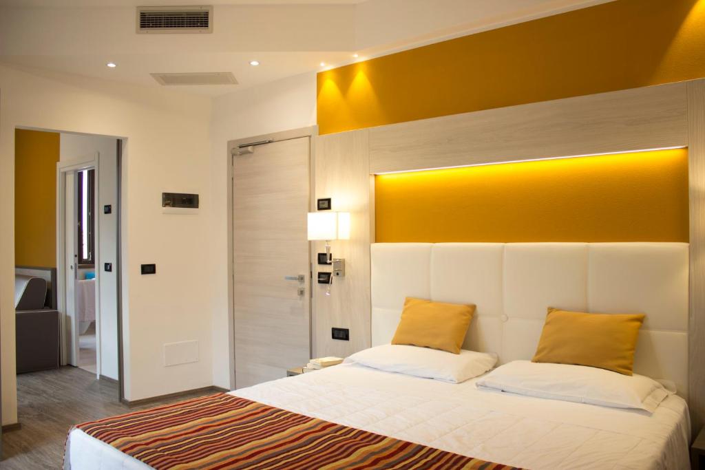 een slaapkamer met een groot bed met een geel hoofdeinde bij Hotel Dolomiti in Malcesine