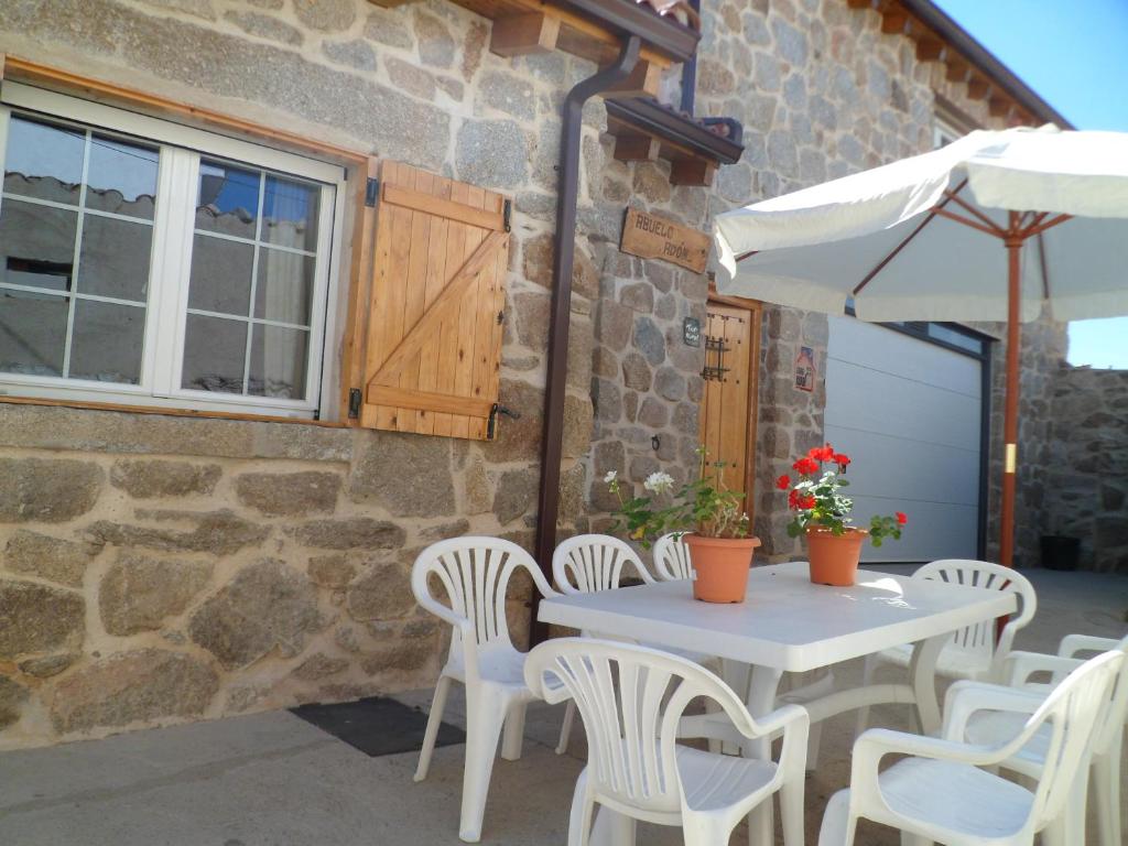 eine Terrasse mit einem Tisch, Stühlen und einem Sonnenschirm in der Unterkunft Casa Rural Abuelo Adón in Baterna