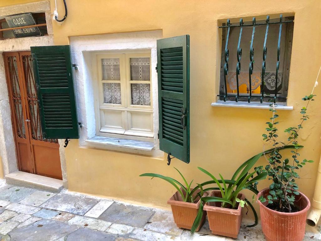 a building with green shutters and plants next to a window at Grandma’s old town house in Corfu Town