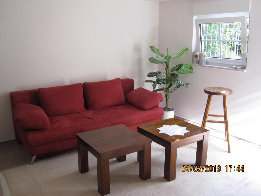 ein Wohnzimmer mit einem roten Sofa und einem Tisch in der Unterkunft Ferien- bzw. Zeitwohnen Burglengenfeld » Apartment 2 in Burglengenfeld