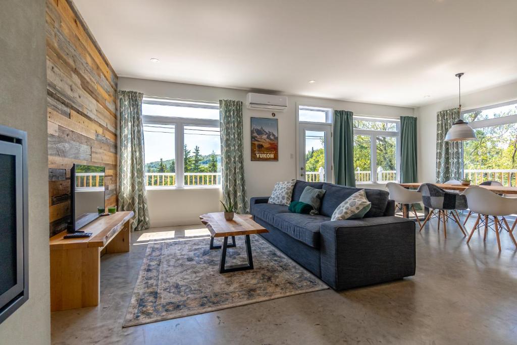 a living room with a couch and a table at Hôtel-Appartements de la Gare in Val-David