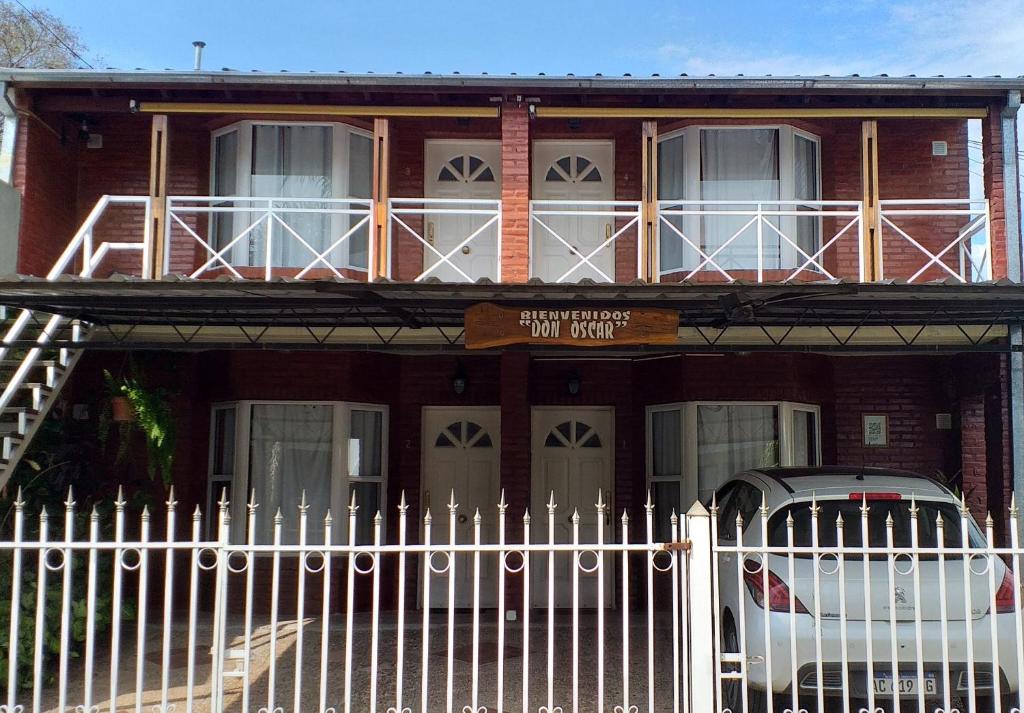 una casa de ladrillo rojo con una valla blanca y un coche en Cabaña Don Oscar en Federación