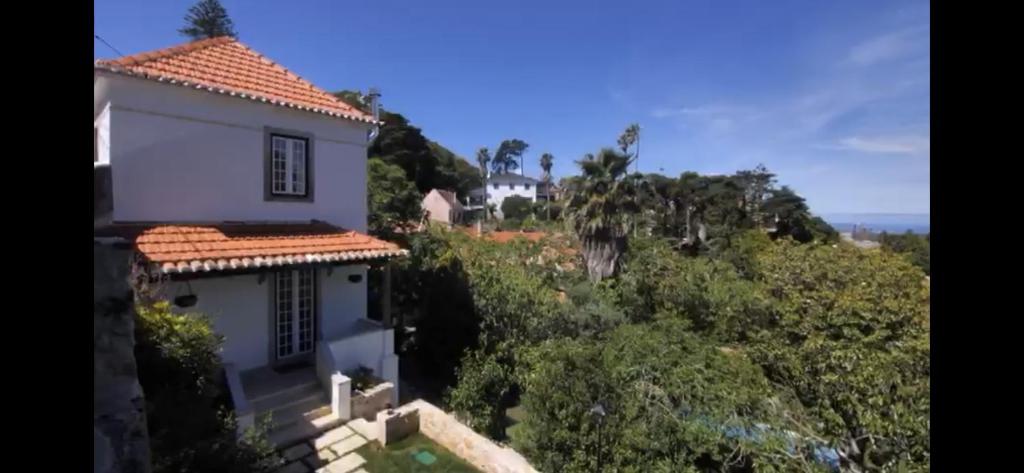 une maison blanche avec un toit en tuiles rouges dans l'établissement Entire House - Romantic Vintage Cottage, à Sintra