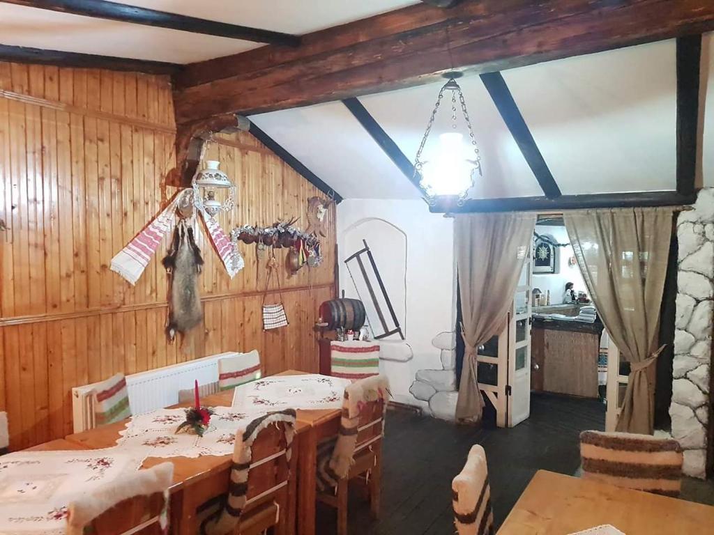 a dining room with a table in a room with wooden walls at Căsuța din Povești in Horea