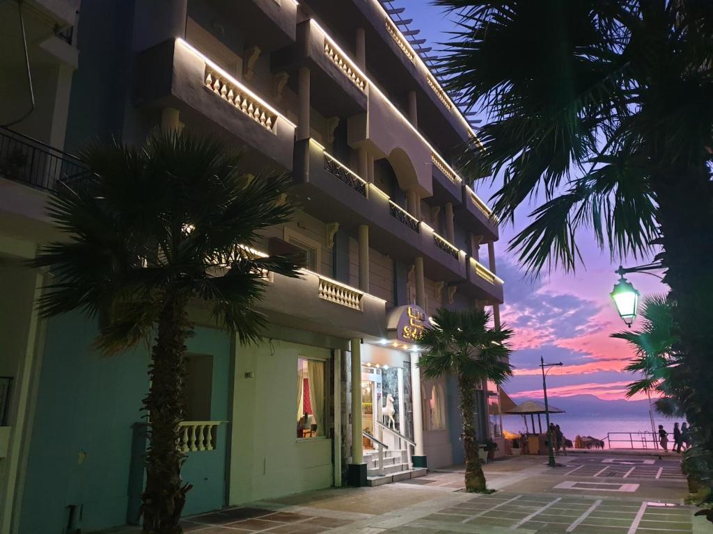 a hotel with palm trees in front of a building at Seaside Hotel in Loutraki