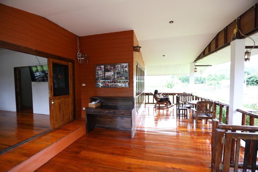 una sala de estar con suelo de madera y una persona sentada en una silla en Hotsia Homestay en Ban Pak Ing