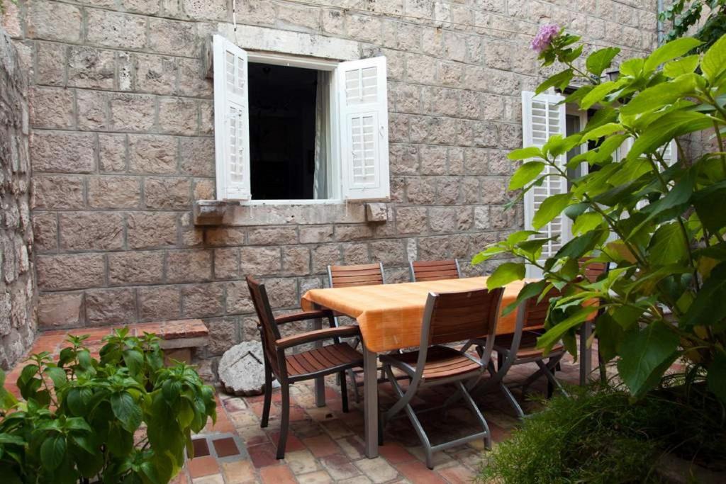 a wooden table and chairs in front of a brick wall at Holiday home Korta - 50 m from sea in Cavtat