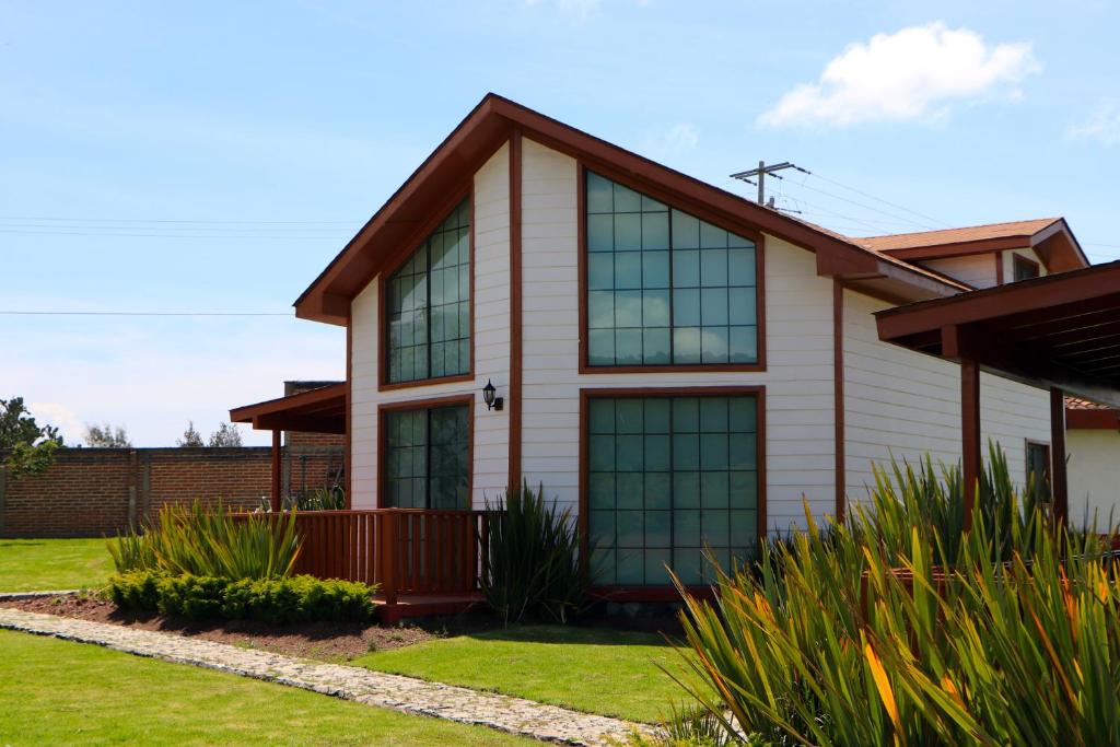 una casa con grandes ventanas en el césped en Cabañas Molino del Rey en Tapalpa