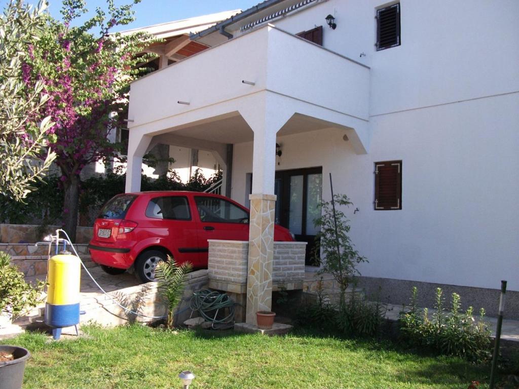 a red car parked in front of a white house at Apartment Dusko - free parking in Gornji Karin