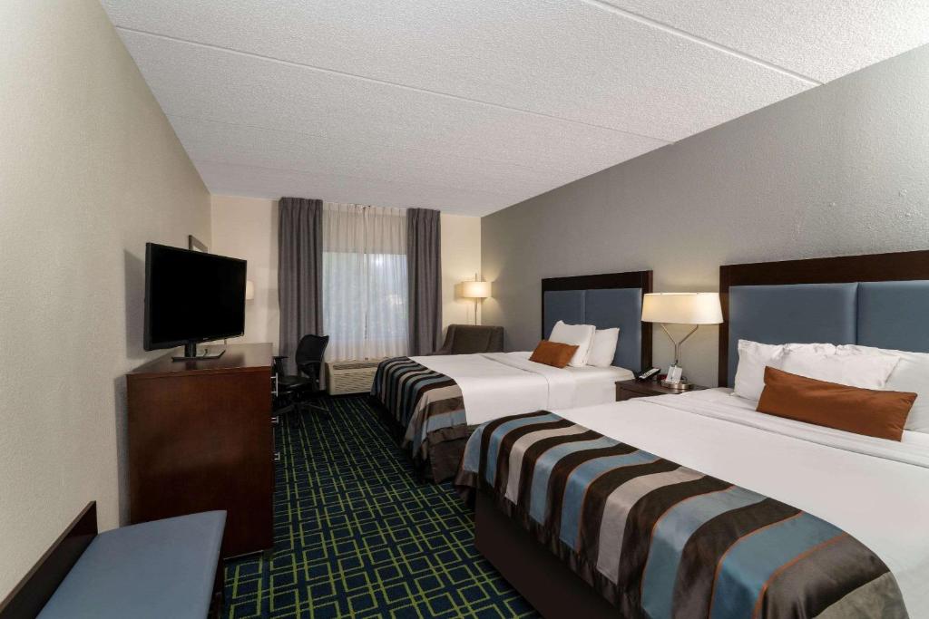 a hotel room with two beds and a flat screen tv at Wingate by Wyndham Fletcher at Asheville Airport in Fletcher