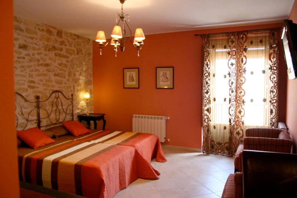 a bedroom with a bed with orange walls and a window at Hostal Mesón Castilla in Sigüenza