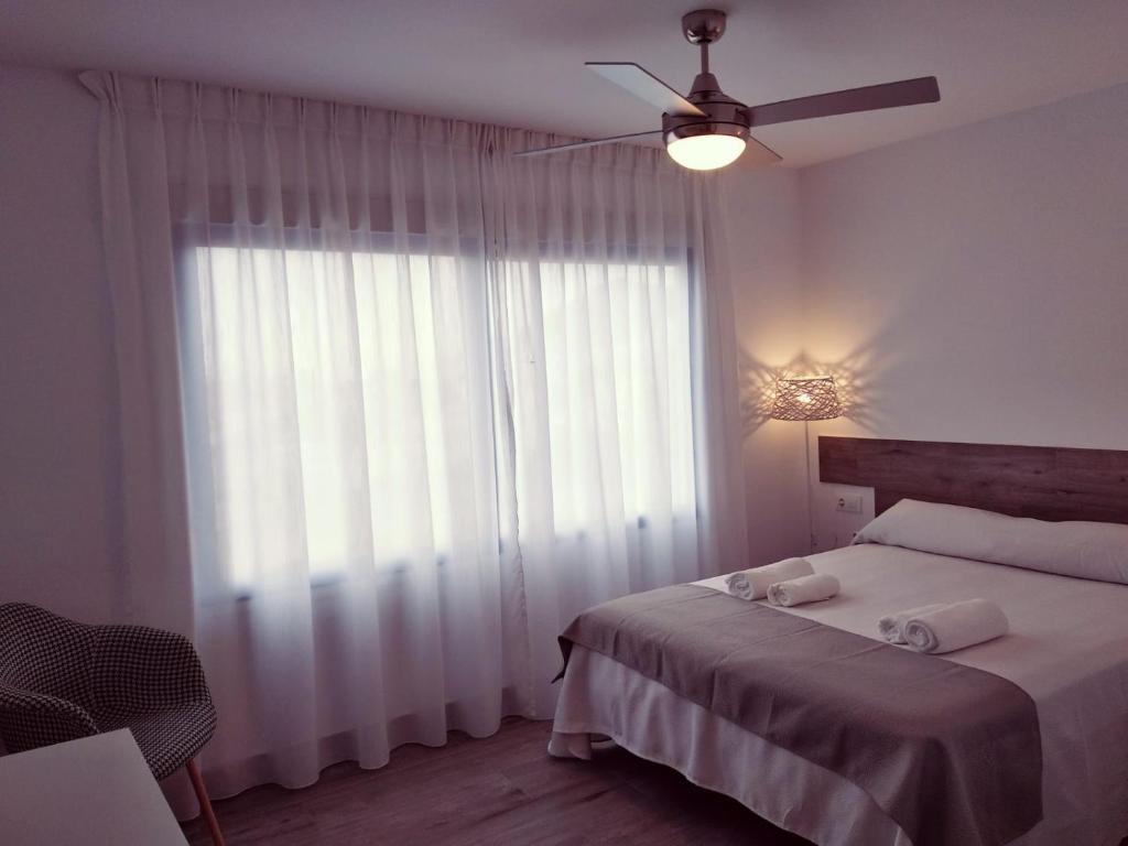 a bedroom with a bed with a ceiling fan and a window at Alojamientos 4nudos in San José