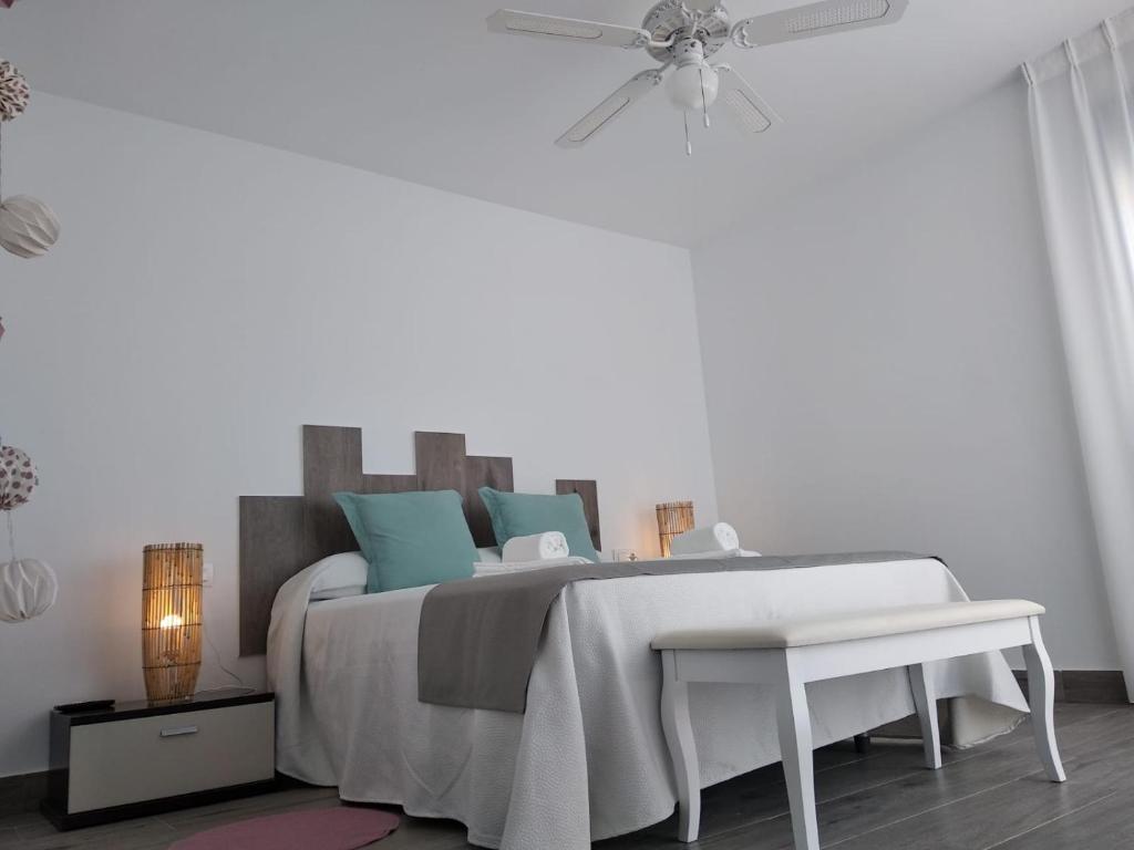 a white bedroom with a bed and a ceiling fan at Alojamientos 4nudos in San José