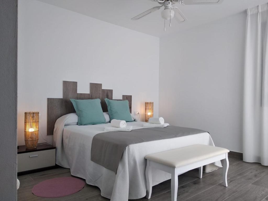 a white bedroom with a large bed with blue pillows at Alojamientos 4nudos in San José