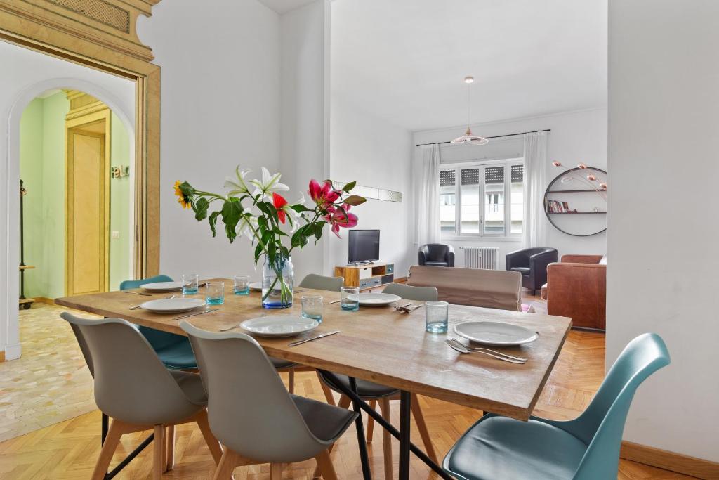 uma mesa de jantar com cadeiras e um vaso de flores em Roomy Apartment Duomo & San Babila em Milão