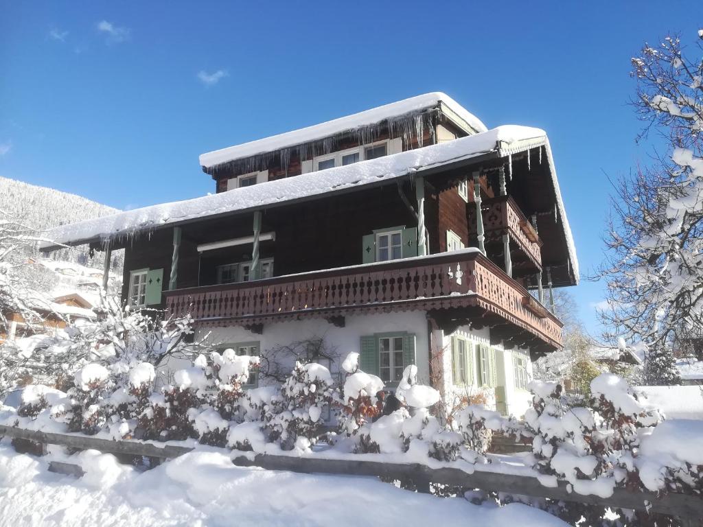 a house covered in snow with trees and bushes at Villa Zeppelin - App Smaragd in Bramberg am Wildkogel