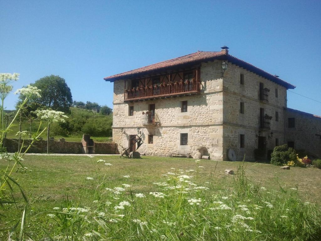 un antiguo edificio de piedra con un balcón de madera. en Casa rural La Toba I y II, en Bezana