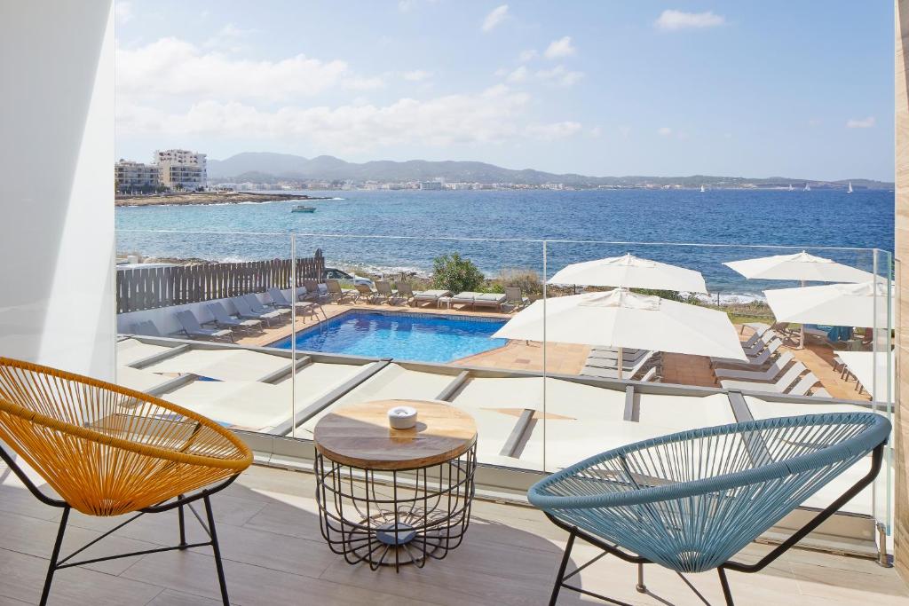 
a patio area with chairs, tables, chairs and umbrellas at Sol Bahía Ibiza Suites in San Antonio
