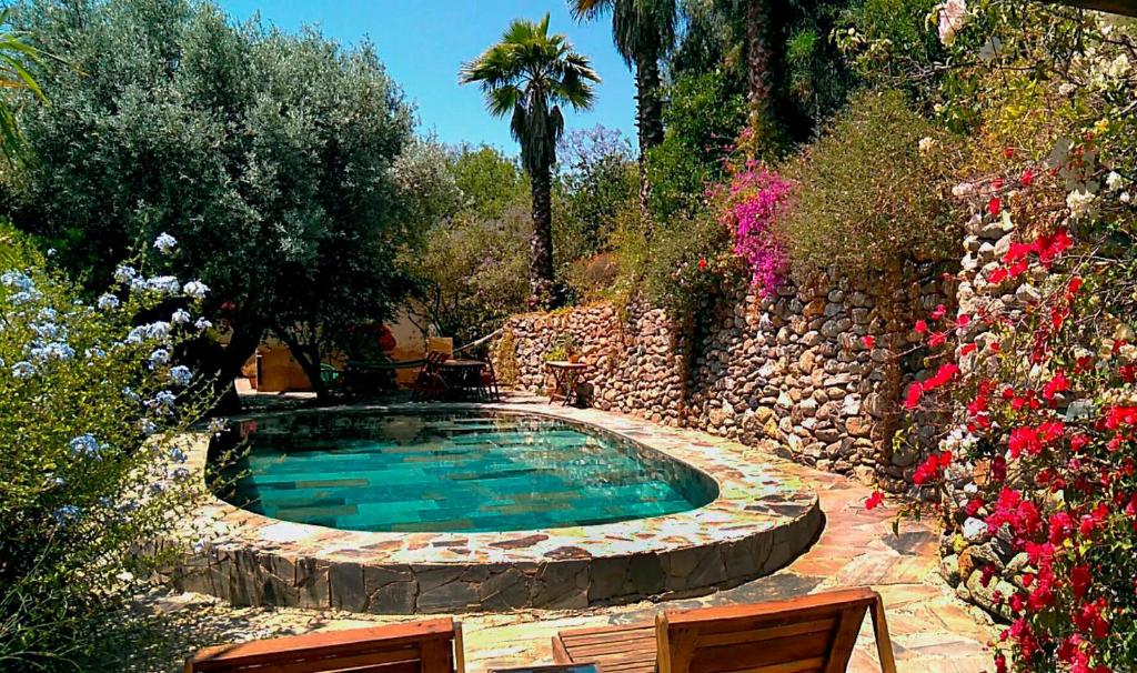 a pool in a garden with two chairs and flowers at Casa Champasak in Órgiva