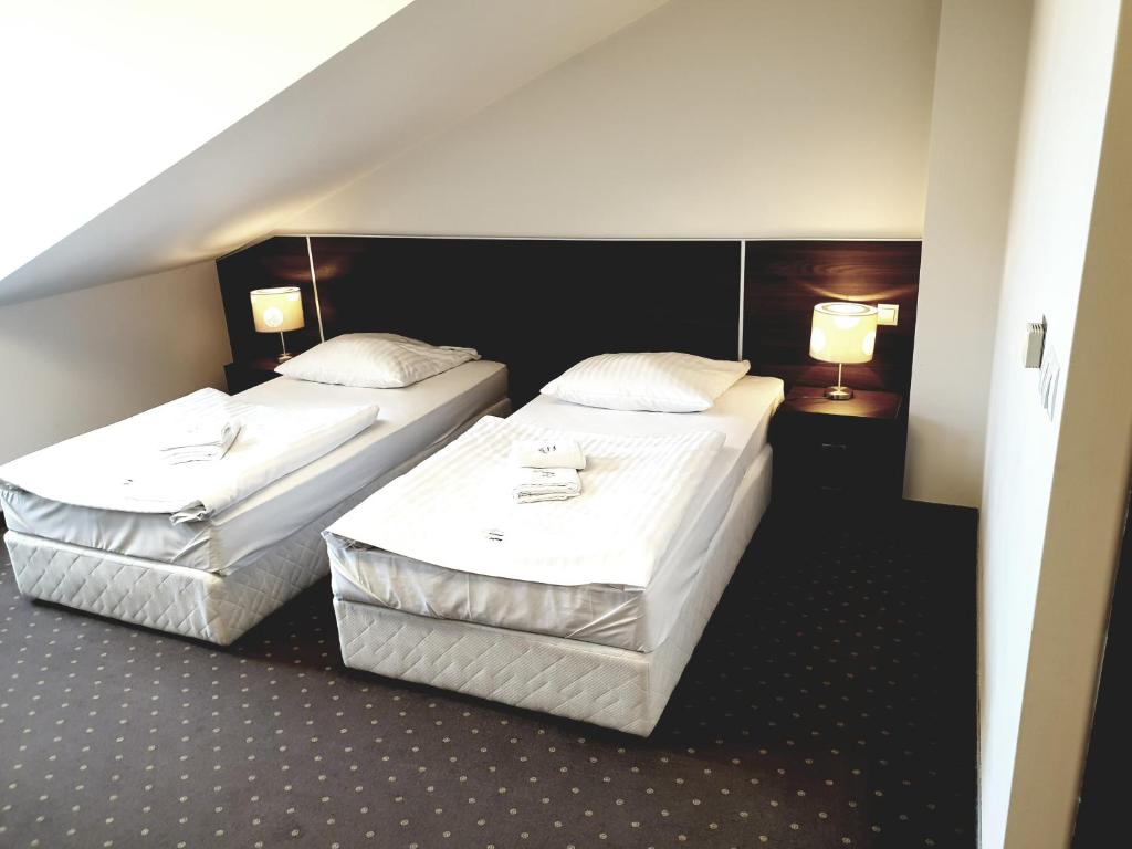 2 camas en una habitación de hotel con 2 lámparas en Perła Podhala, en Szaflary
