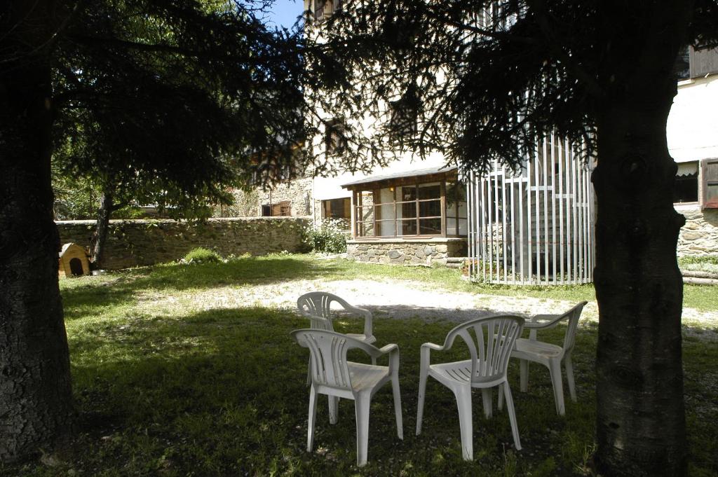 three chairs and a table under a tree at Xalet-Refugi U.E.C. in La Molina