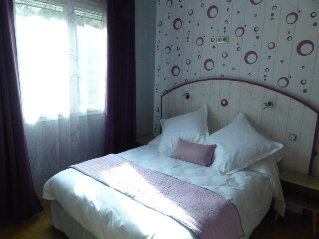 a bedroom with a large white bed with a wall at AU CLOS DE L'ETANG in Ravel