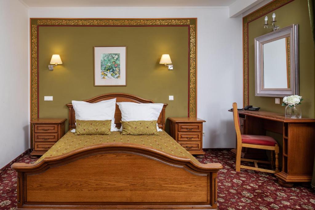 a bedroom with a large wooden bed with a desk at Grand Hotel in Braşov