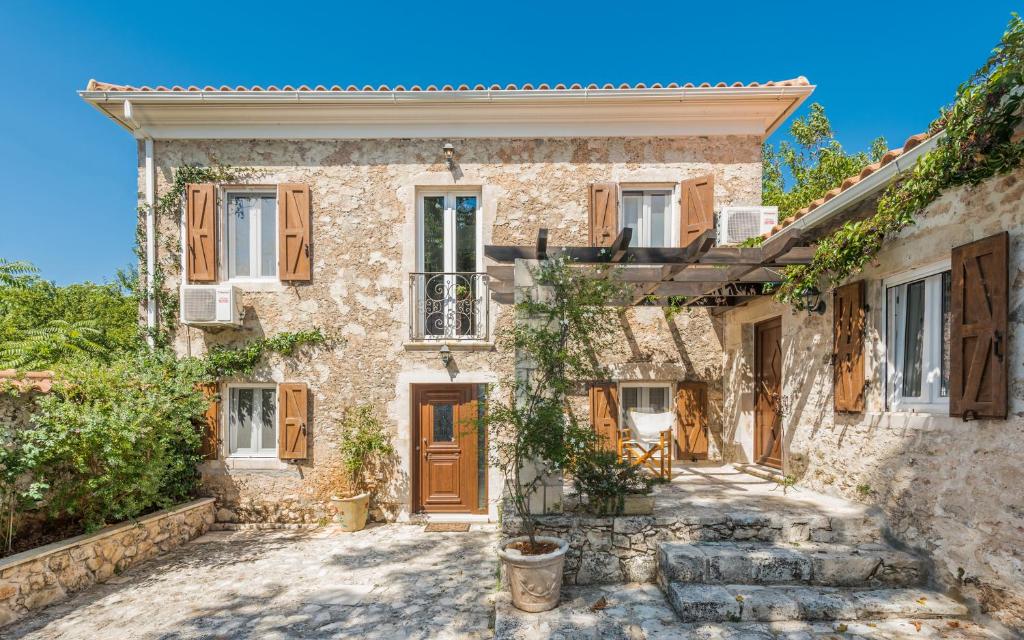 an old stone house with wooden doors and windows at Villa Callisto- Elegant Villa with Pool in Yírion