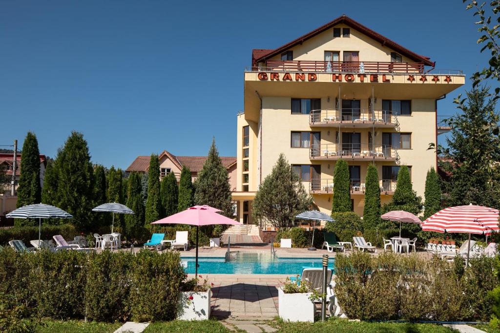 un hotel con piscina, sedie e ombrelloni di Grand Hotel a Braşov