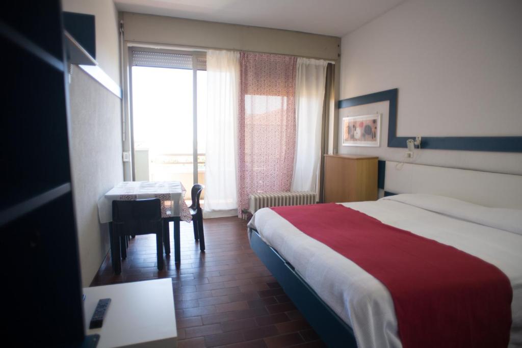 una camera d'albergo con letto, scrivania e finestra di Residence Carducci a Cesenatico