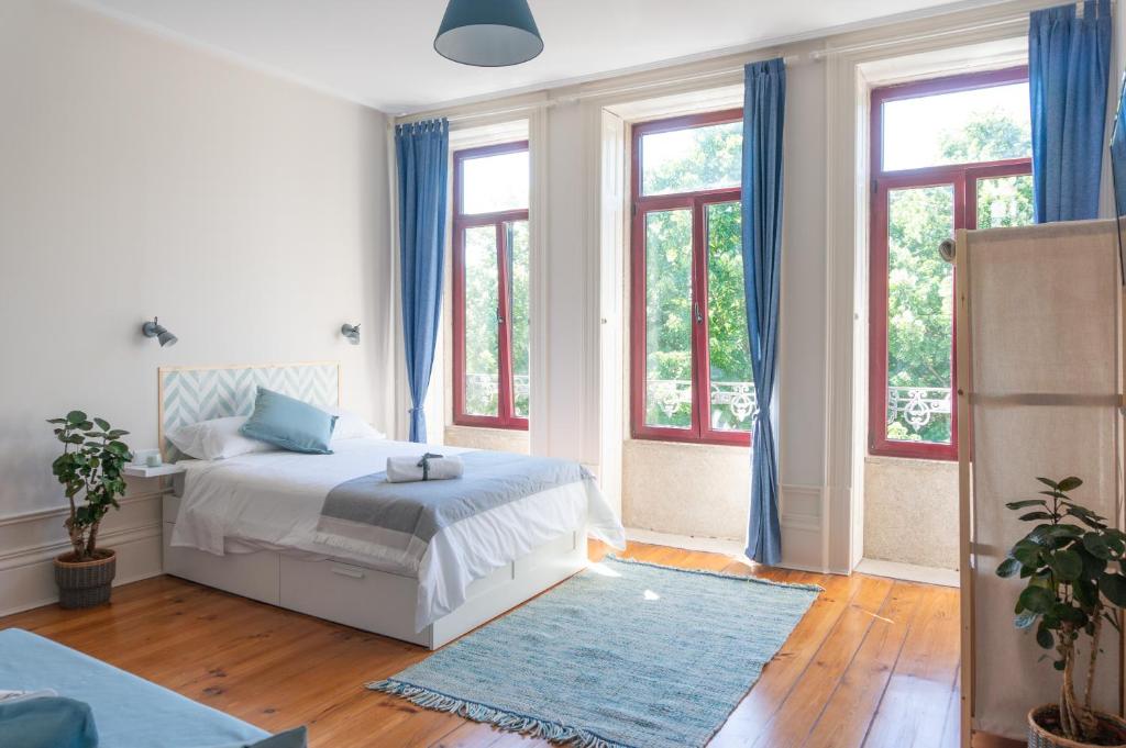 a bedroom with a bed with blue curtains and windows at Jardim de São Lázaro - Porto Apartments in Porto